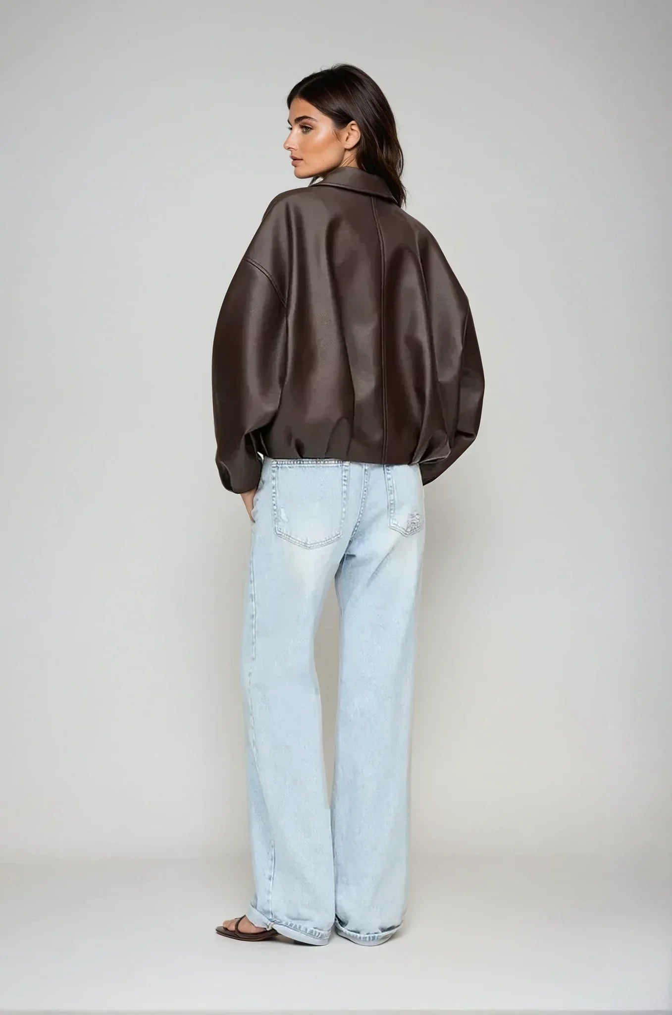 model trägt schwarze oversized vegan-leder jacke mit gürtel und zip
