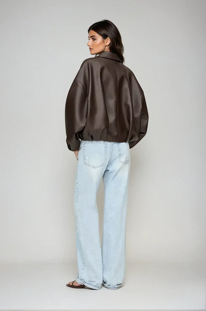 model trägt schwarze oversized vegan-leder jacke mit gürtel und zip