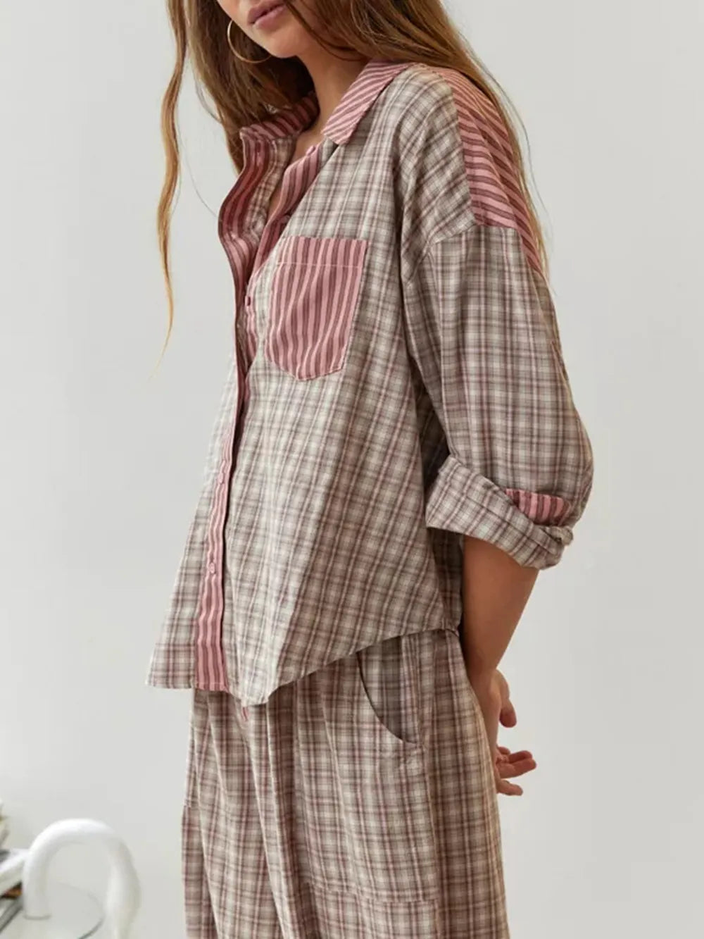 Eine Frau trägt ein 2-teiliges braunes, lässiges Pyjama-Set mit Karomuster