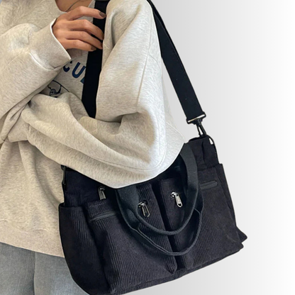 Frau trägt schwarze Cord-Schultertasche mit Reißverschluss