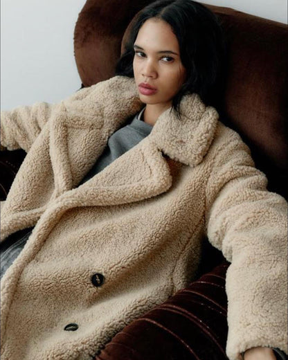 Luxe Teddy Mantel beige, getragen auf Sofa
