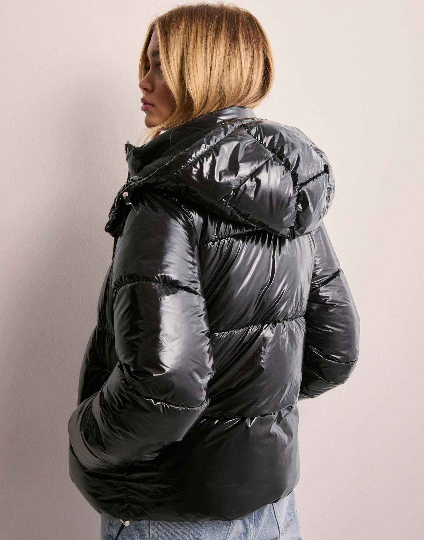 nahaufnahme schwarze pufferjacke mit glänzendem stoff und reißverschluss