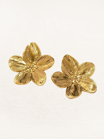 Paar Blumen-Ohrringe gold auf hellem Hintergrund

