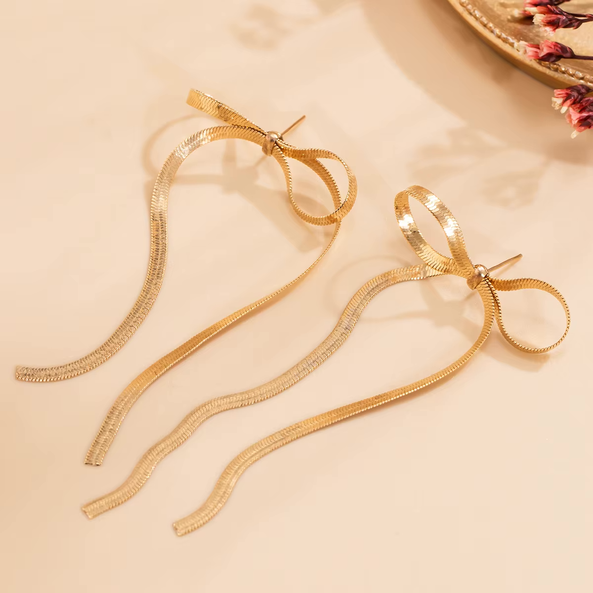 Paar Liora Bow Ohrringe in Gold und Silber auf Stoff
