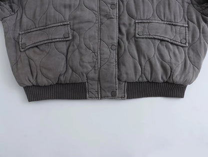Eine Nahaufnahme des Saums und der Manschetten einer grauen Bomberjacke, die ihr strukturiertes Design zeigt.